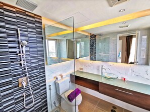 A modern bathroom with a glass shower enclosure, a large mirror, and a marble countertop. - Grande Caribbean Resort (Pattaya)