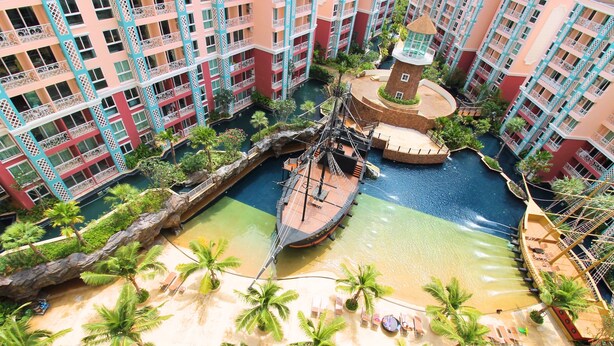 A resort with multiple buildings, a water park, and a sandy beach area with palm trees. - Grande Caribbean Resort (Pattaya)