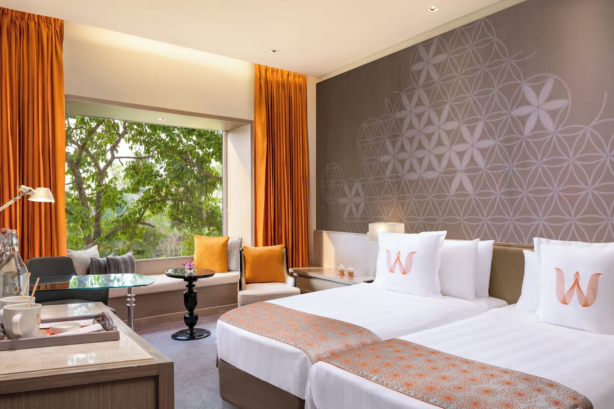 A hotel room with a large bed, a desk, a chair, and a window with curtains.