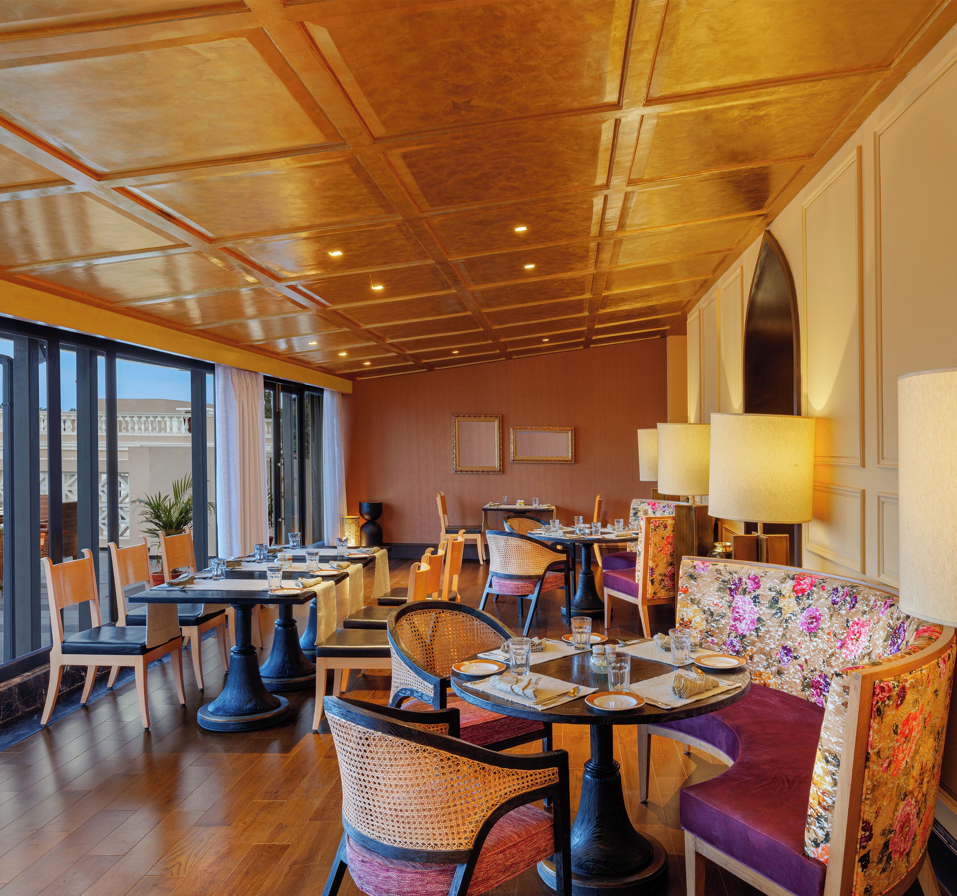A restaurant with wooden ceiling, tables with chairs, and a large window.