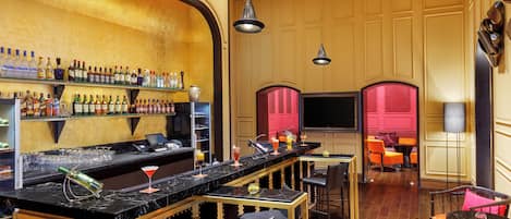 A bar area with a long counter, multiple shelves of bottles, and bar stools.