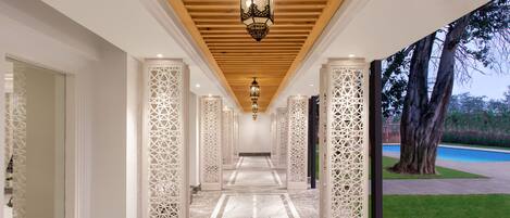 A corridor with a wooden ceiling, decorative lanterns, and patterned columns.