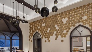 A modern restaurant with high tables, cushioned booths, and a decorative wall with geometric patterns. - Welcomhotel by ITC Hotels, Raja Sansi, Amritsar (Amritsar)