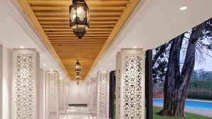 A corridor with intricate white lattice panels, a wooden ceiling, and a hanging lantern. - Welcomhotel by ITC Hotels, Raja Sansi, Amritsar (Amritsar)