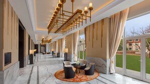 A spacious lobby with a marble floor, a central seating area with chairs and a table, and a large chandelier. - Welcomhotel by ITC Hotels, Raja Sansi, Amritsar (Amritsar)