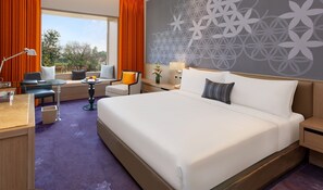 A hotel room with a large bed, a desk with a chair, a small table, and a window with curtains. - Welcomhotel by ITC Hotels, Raja Sansi, Amritsar (Ajnala)