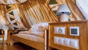 A cozy attic bedroom with a wooden bed, a lamp, a thermostat, and a coffee maker.