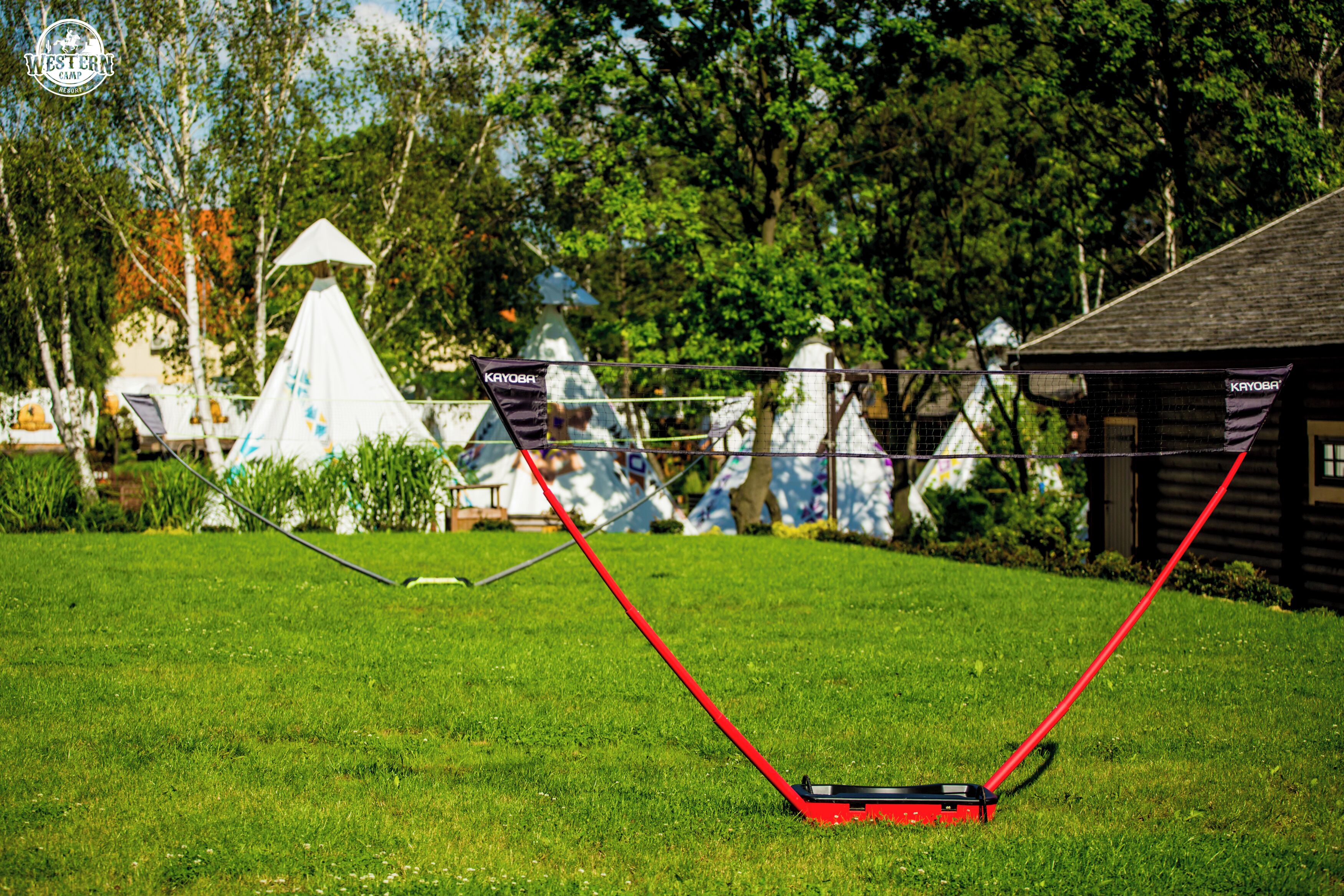 A grassy area with a red lawnmower and a white tent in the background.