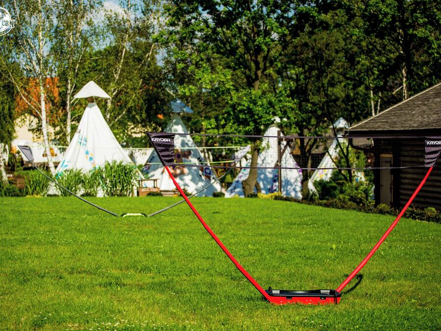 A grassy area with a red lawnmower and a white tent in the background.