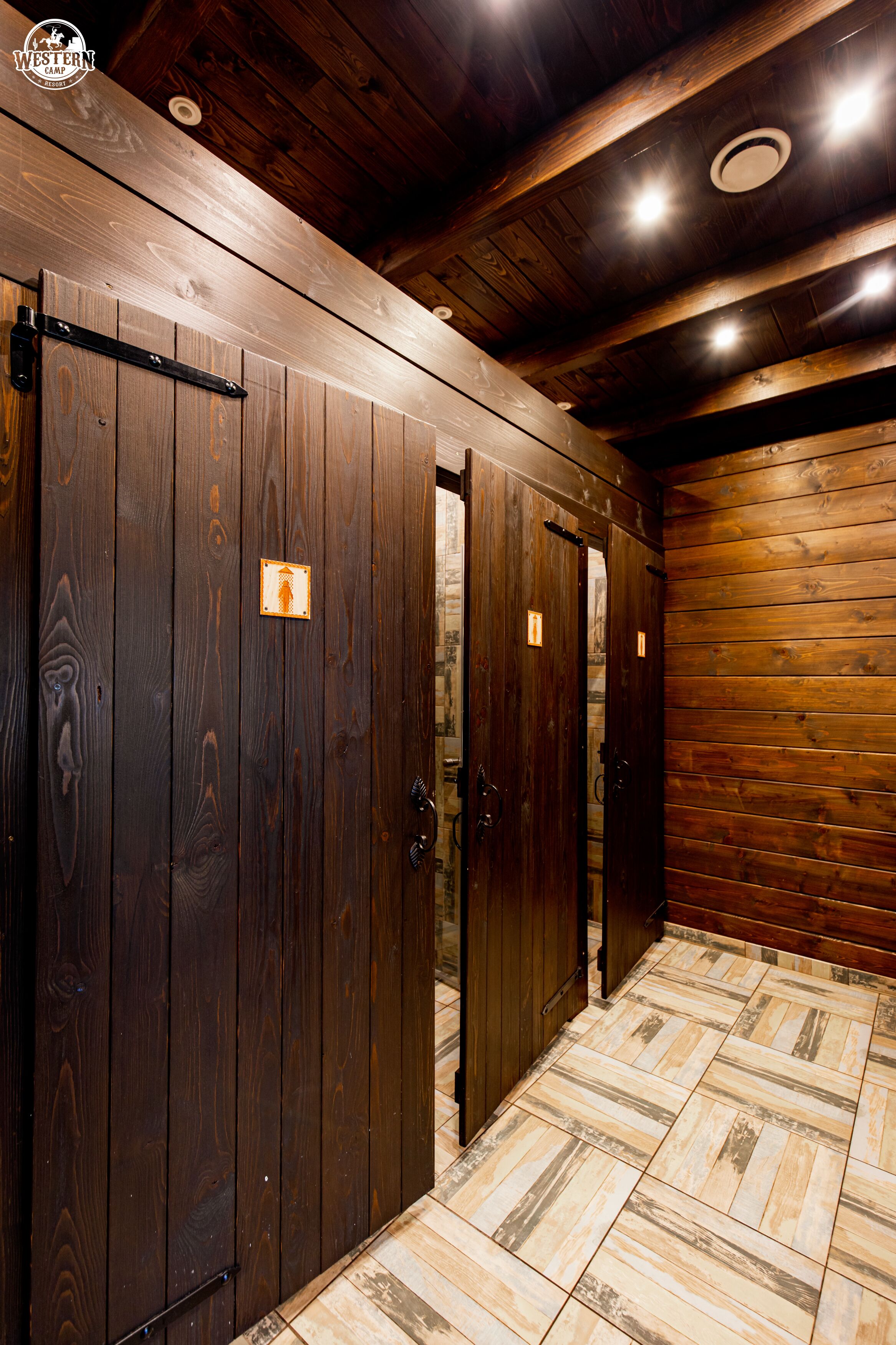 A wooden interior with a tiled floor and a door with a small sign.