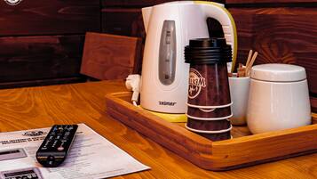 A wooden table with a white kettle, a brown mug, a white cup, and a remote control.
