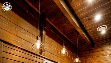 Une longue salle de bain en bois, dotée de trois lavabos, de miroirs et de luminaires suspendus.