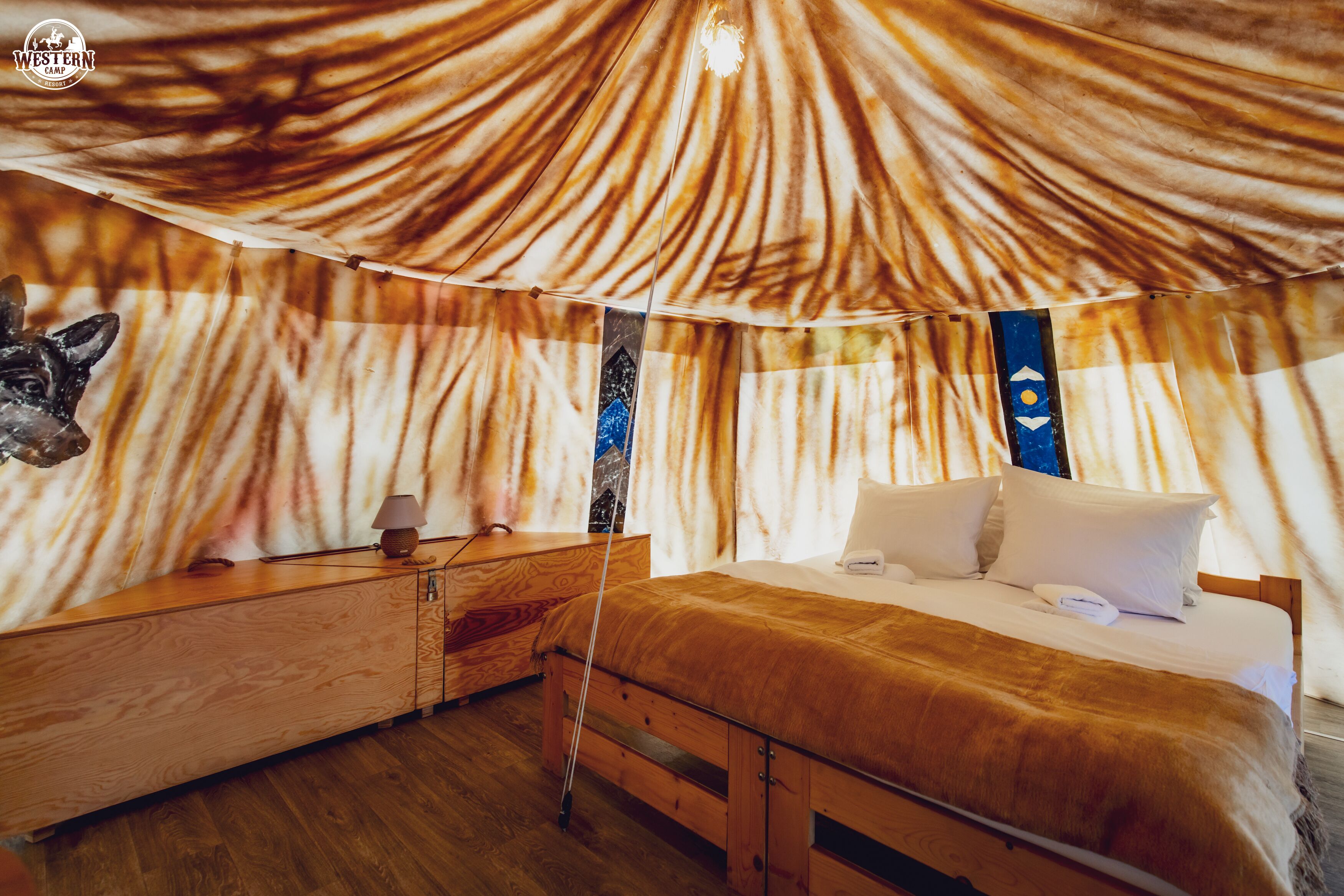 Una habitación tipo tienda de campaña con una cama, muebles de madera y una pared con un diseño único.