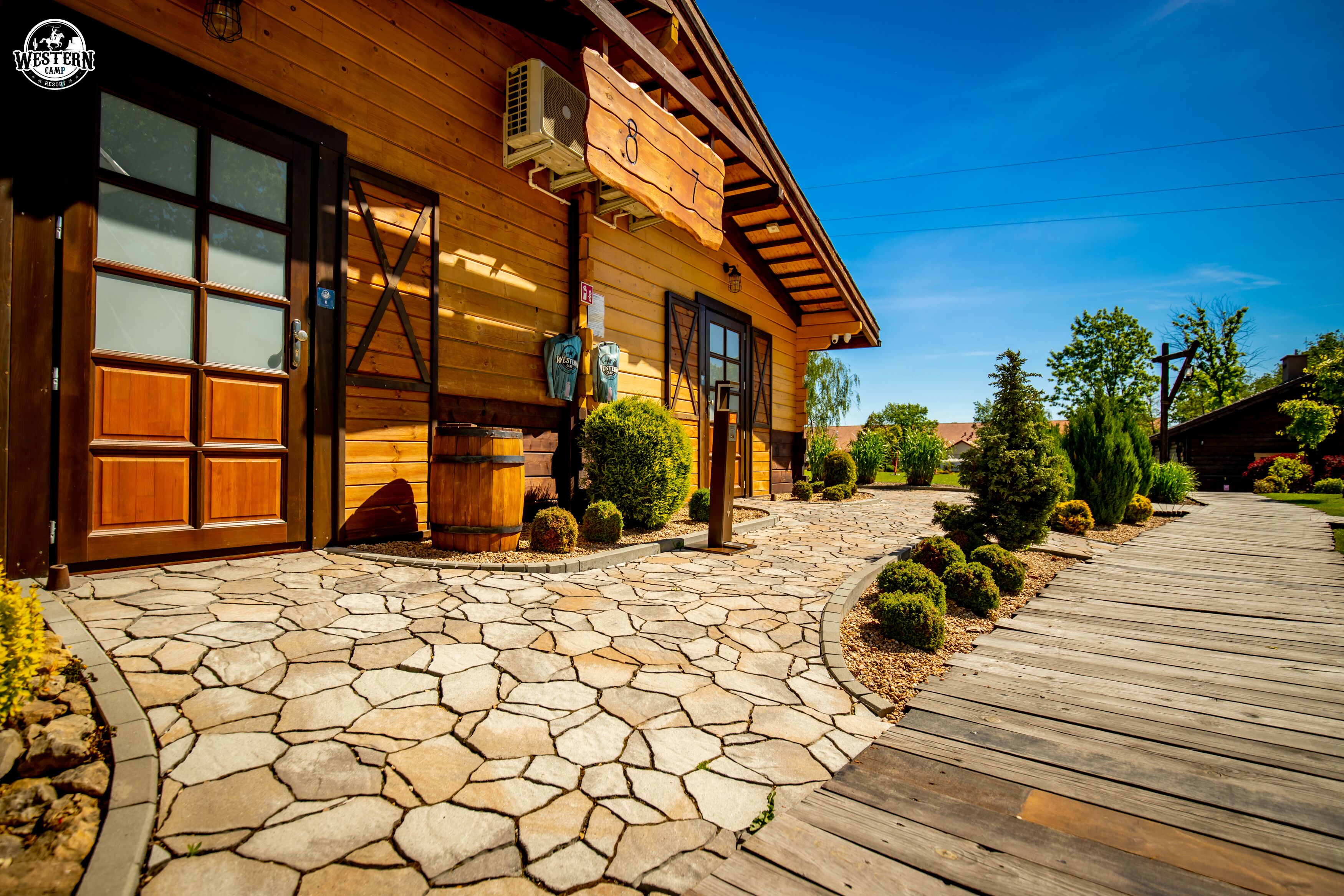 Une cabane en bois avec une entrée pavée de pierres et une terrasse en bois.
