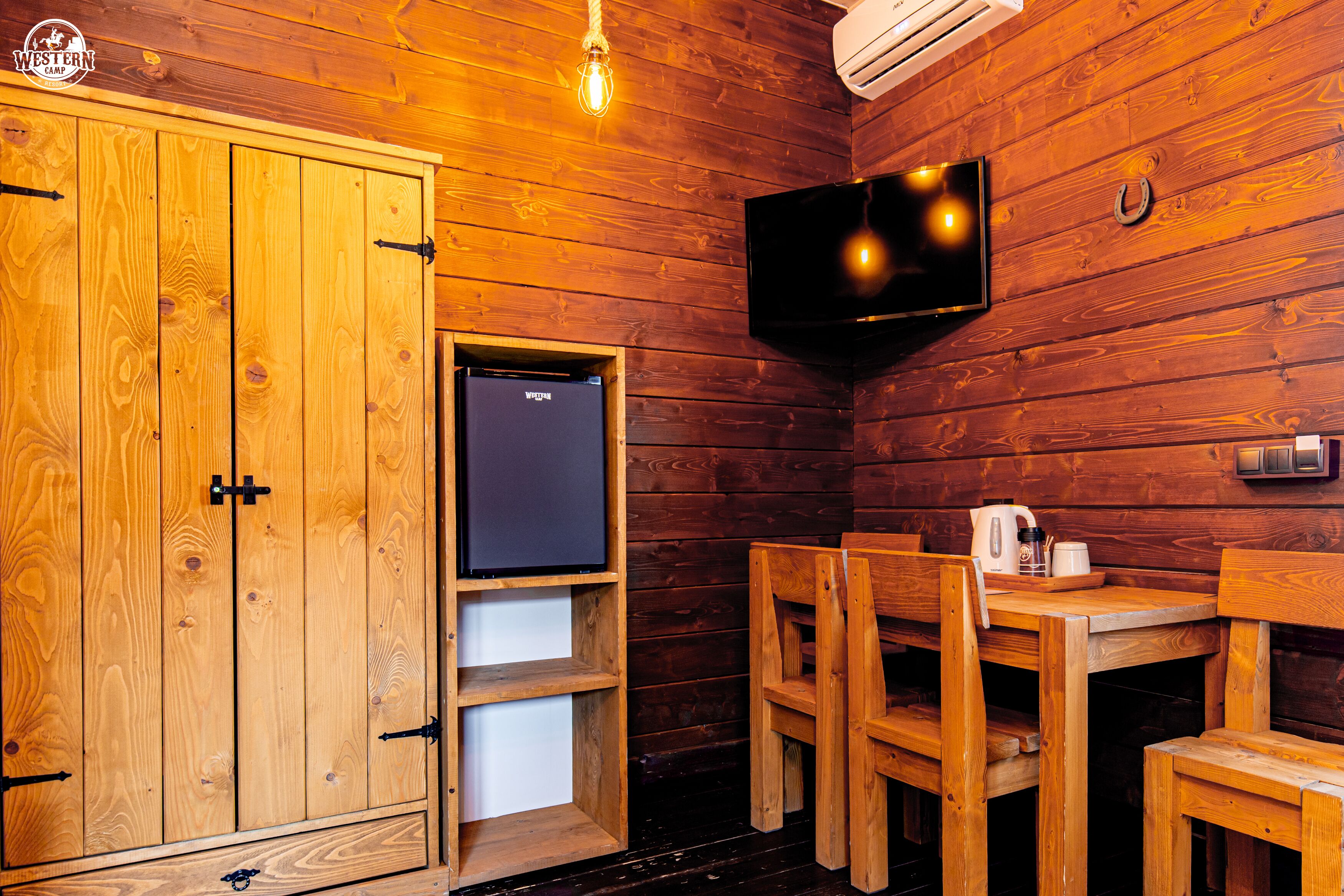 L’intérieur d’une cabane en bois, avec un téléviseur, des meubles en bois et une petite étagère.