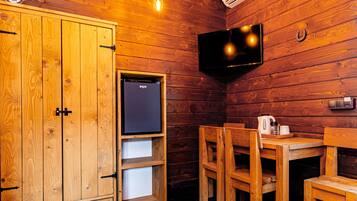 L’intérieur d’une cabane en bois, avec un téléviseur, des meubles en bois et une petite étagère.
