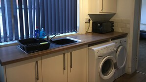 A compact kitchen with a washing machine, a microwave, and a sink. - Brooklyn Place (Crewe)