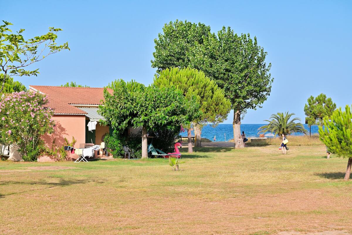 A house with a red roof, a lawn, and a view of the sea.