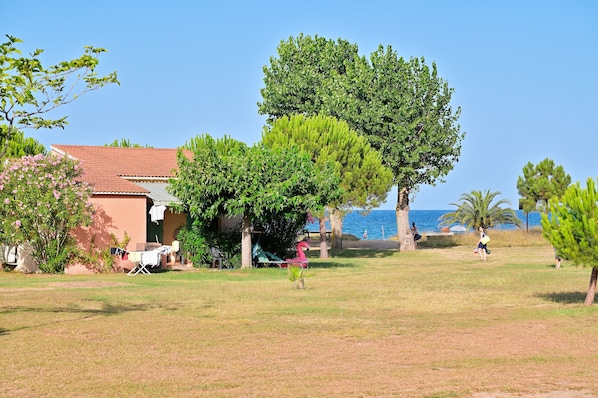 A house with a red roof, a lawn, and a view of the sea.