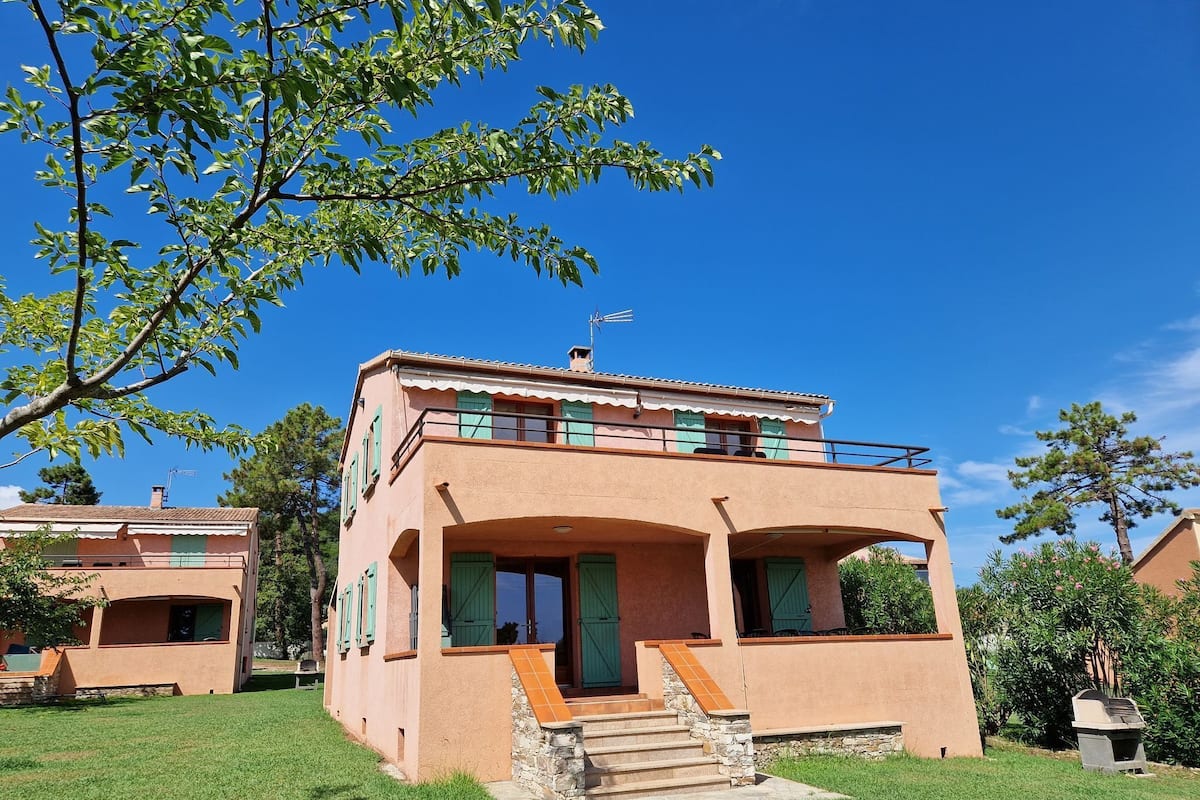 A two-story building with a balcony, stone steps, and a clear blue sky.