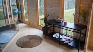 A wooden interior with a glass door leading outside, a woven mat on the floor, a black metal shelf with shoes and a basket, and a vase with flowers. - Villa Royal with heated pool and sauna (Biograd na moru)