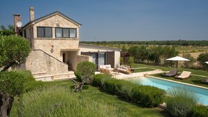 A stone house with a pool, outdoor seating, and a view of the countryside. - Villa Royal with heated pool and sauna (Biograd na moru)