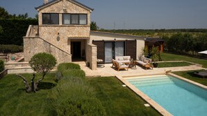 A modern house with a stone exterior, a swimming pool, and outdoor furniture. - Villa Royal with heated pool and sauna (Biograd na moru)