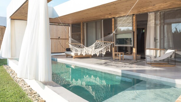 Ett modernt hus med en swimmingpool, en hängmatta och ett trädäck.