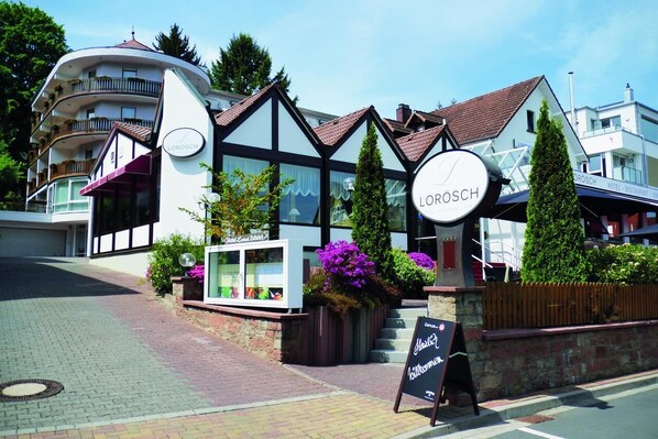 A hotel named 'LOROSCH' with a traditional European architectural style, featuring a prominent clock and a signboard.