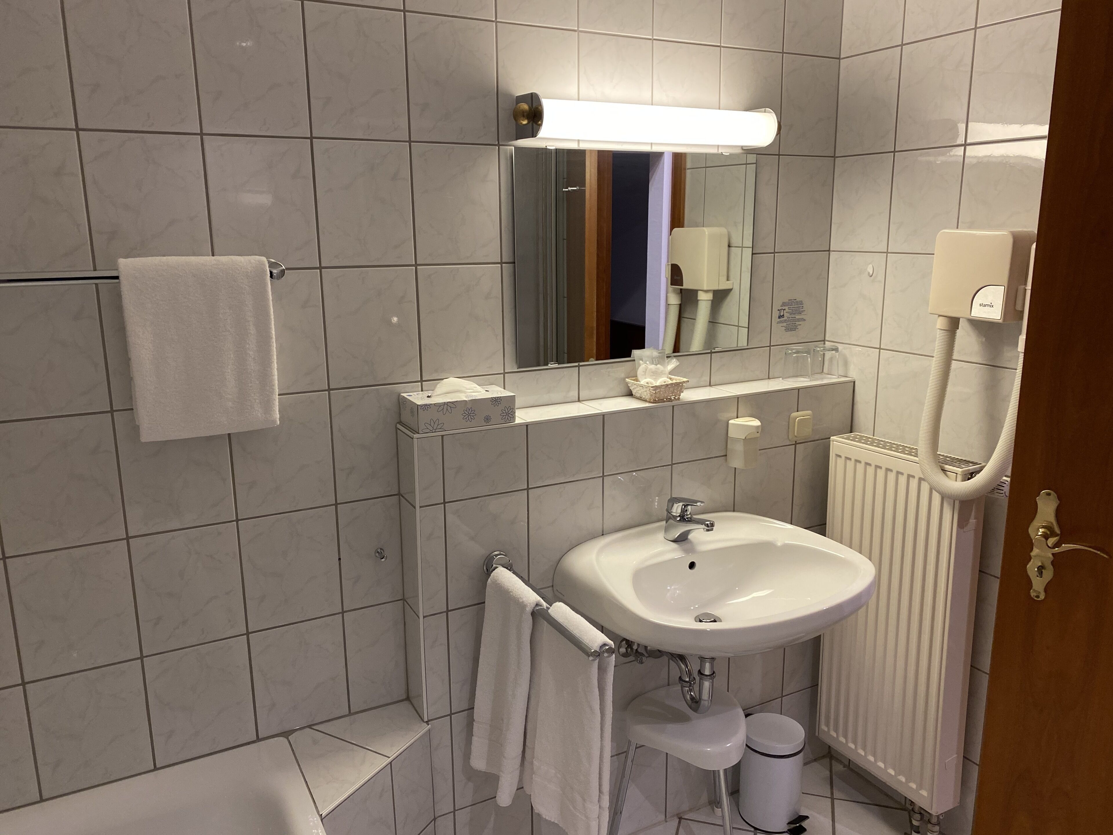 A modern bathroom with a white sink, mirror, and towel rack.