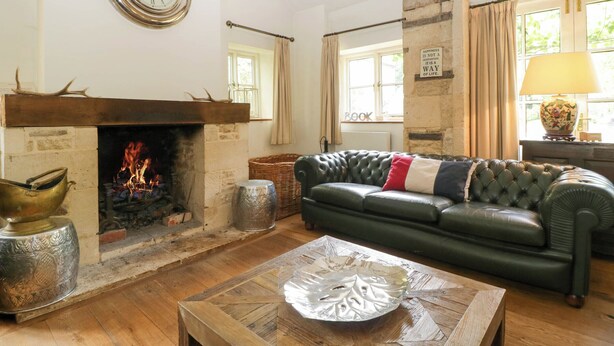 Ein gemütliches Wohnzimmer mit Kamin, einer Ledersofa und einem Holztisch.