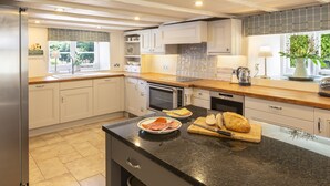 A modern kitchen with white cabinets, a black countertop, and stainless steel appliances. - Higher Collaton Cottage (Kingsbridge)