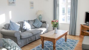 A living room with a grey sofa, a wooden coffee table, and a blue patterned rug. - Cindy's Retreat (Kingsbridge)
