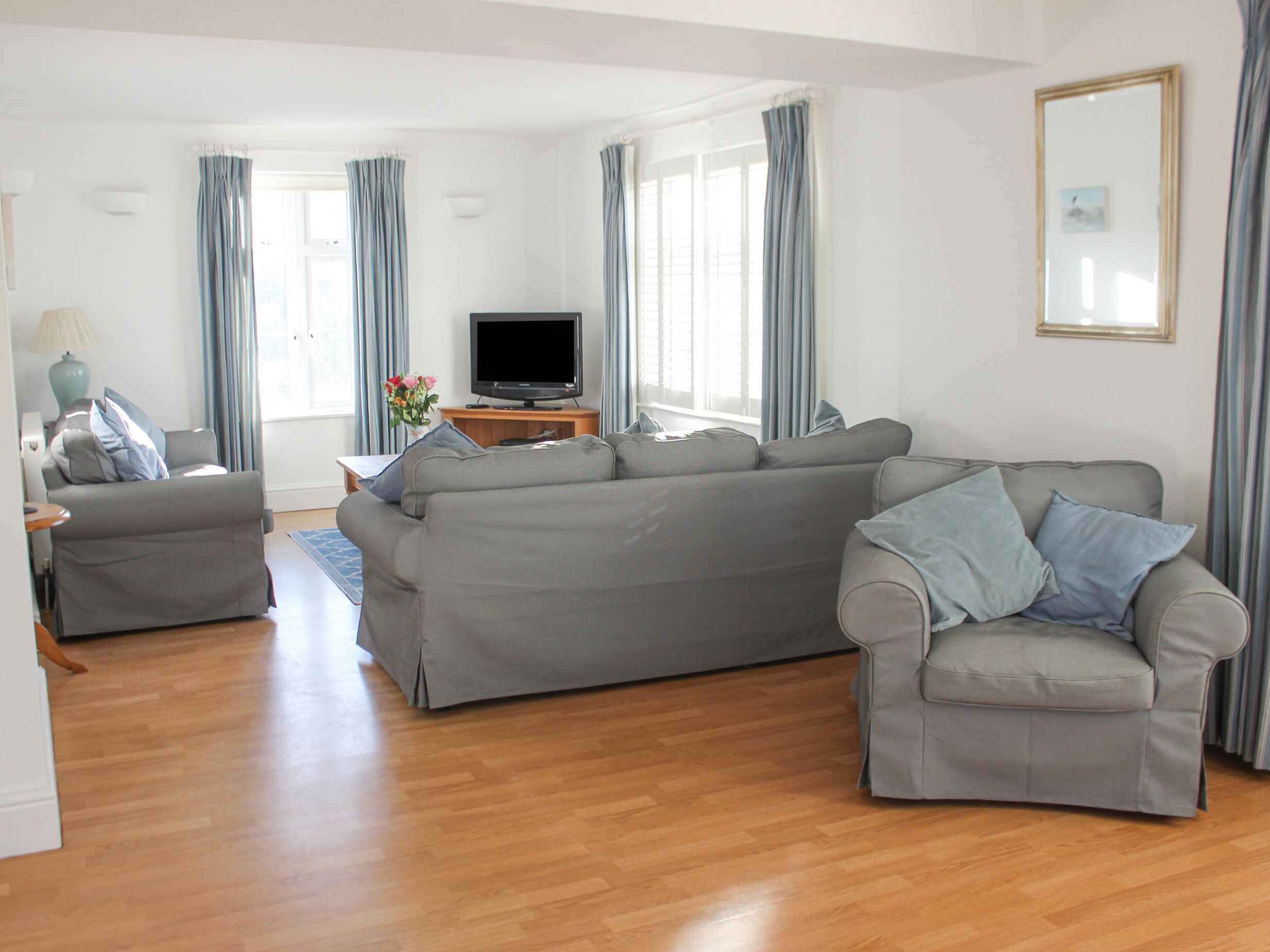 A modern living room with a grey sofa, a grey armchair, and a wooden coffee table.
