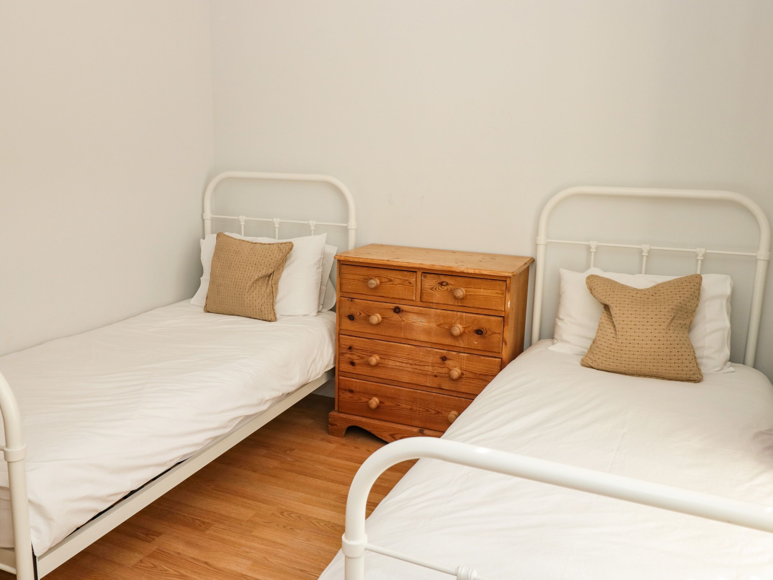 A room with two single beds, each with a wooden dresser in between.