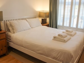 Restful retreat with a made bed, towels, and a bedside table with a lamp and clock.