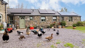 Un edificio de piedra con camino de grava y paneles solares en el techo.