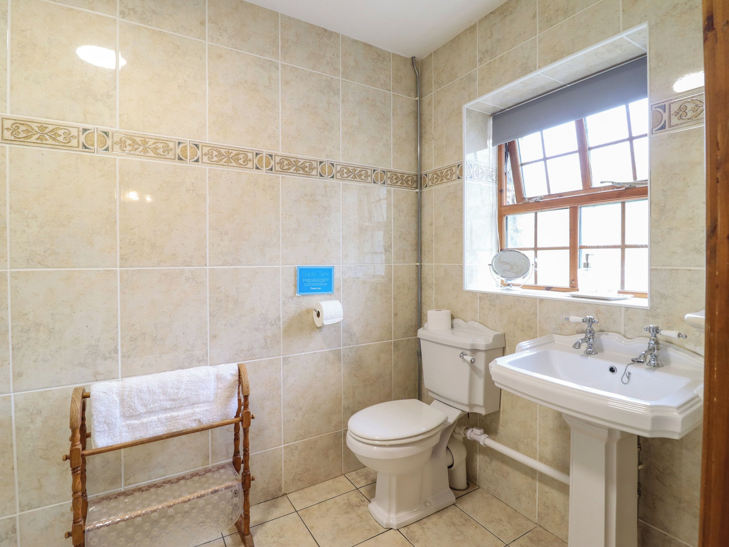 Un baño con inodoro, lavamanos y perchero para toallas.