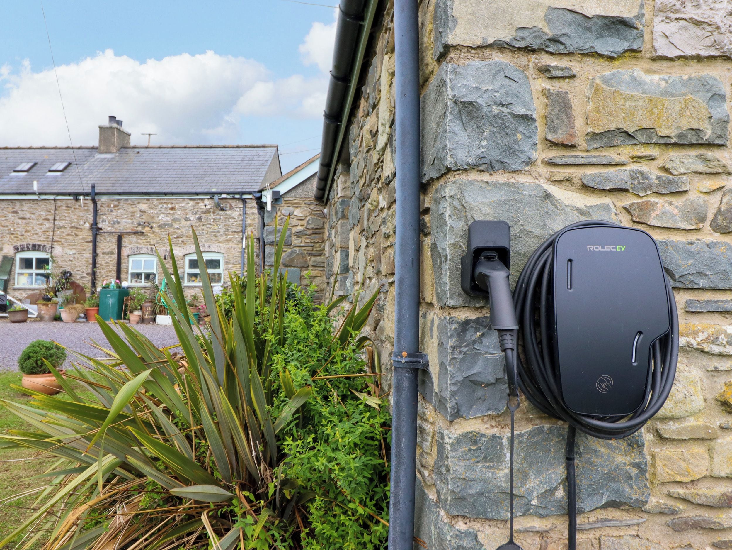 A stone building with a wall-mounted electric vehicle charging station.