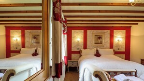 Habitación de hotel con dos camas, techo de madera y lámparas fijadas a la pared.
