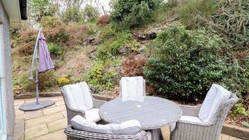 A patio with wicker furniture and a small umbrella.