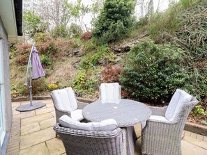 Une terrasse avec des meubles en osier et un petit parasol.