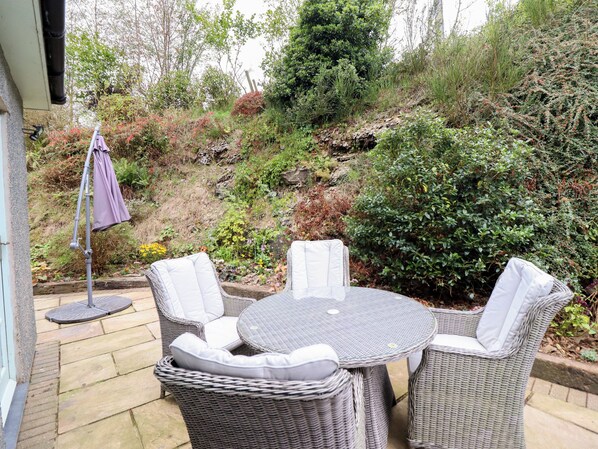 A patio with wicker furniture and a small umbrella.