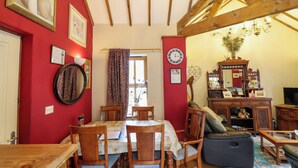 Una habitación con una mesa de comedor, sillas, un sofá, un televisor y una estructura de techo de madera.