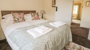 Un lit bien fait, agrémenté d’oreillers à motifs floraux, d’une couvre-lit à dessins et de serviettes pliées posées sur le bord.