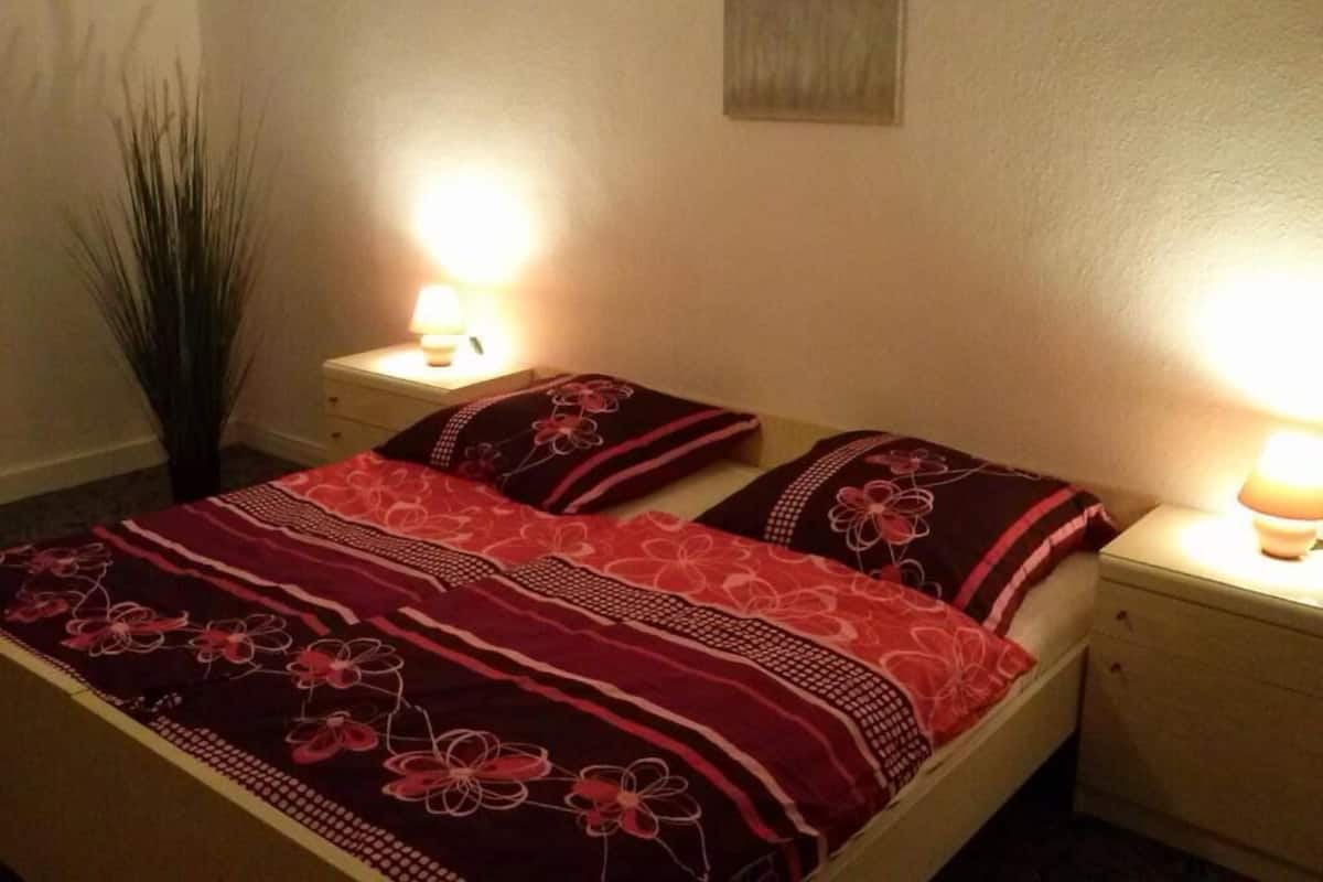 A bed with a floral-patterned bedspread and two pillows, flanked by bedside tables with lamps.