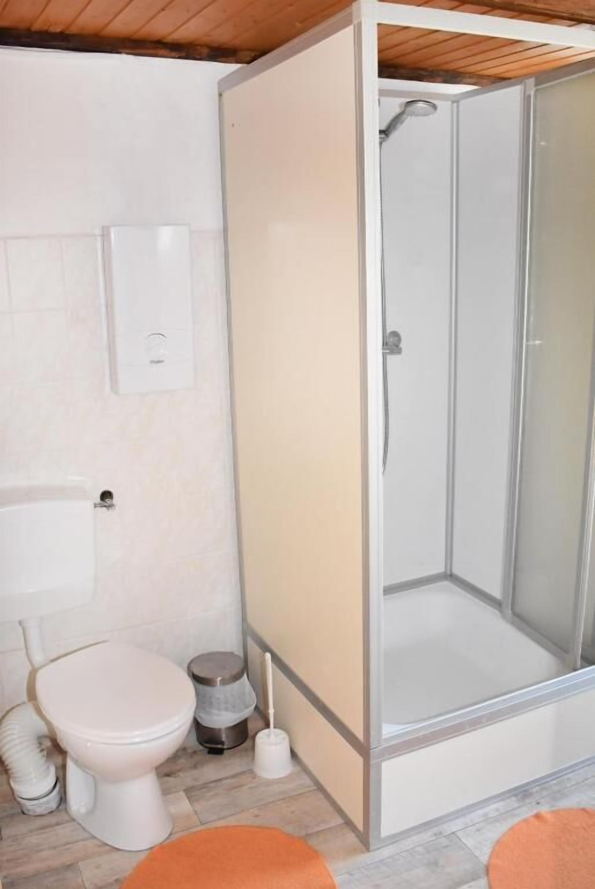 Un baño con inodoro, lavamanos y ducha con mampara de vidrio.
