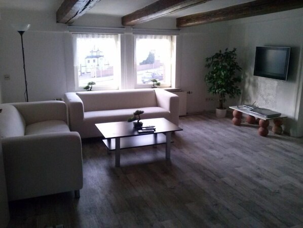 A living room with a sofa, a coffee table, a TV, and a plant.