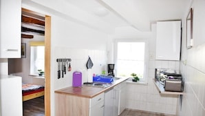 A compact kitchen with white cabinets, a wooden countertop, and a window providing natural light. - Ferienwohnung Langelsheim (Langelsheim)