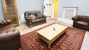 A living room with a leather sofa, a wooden coffee table, and a patterned rug. - No 1 Church Cottages (Llanelli)